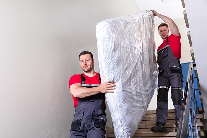 tackling the task of transporting a box spring out of a building in Estero